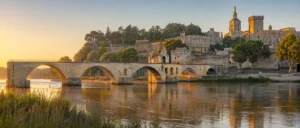 Vue panoramique du Pont d'Avignon Saint-Bénézet au bord du Rhône avec les remparts et le Palais des Papes en arrière-plan.