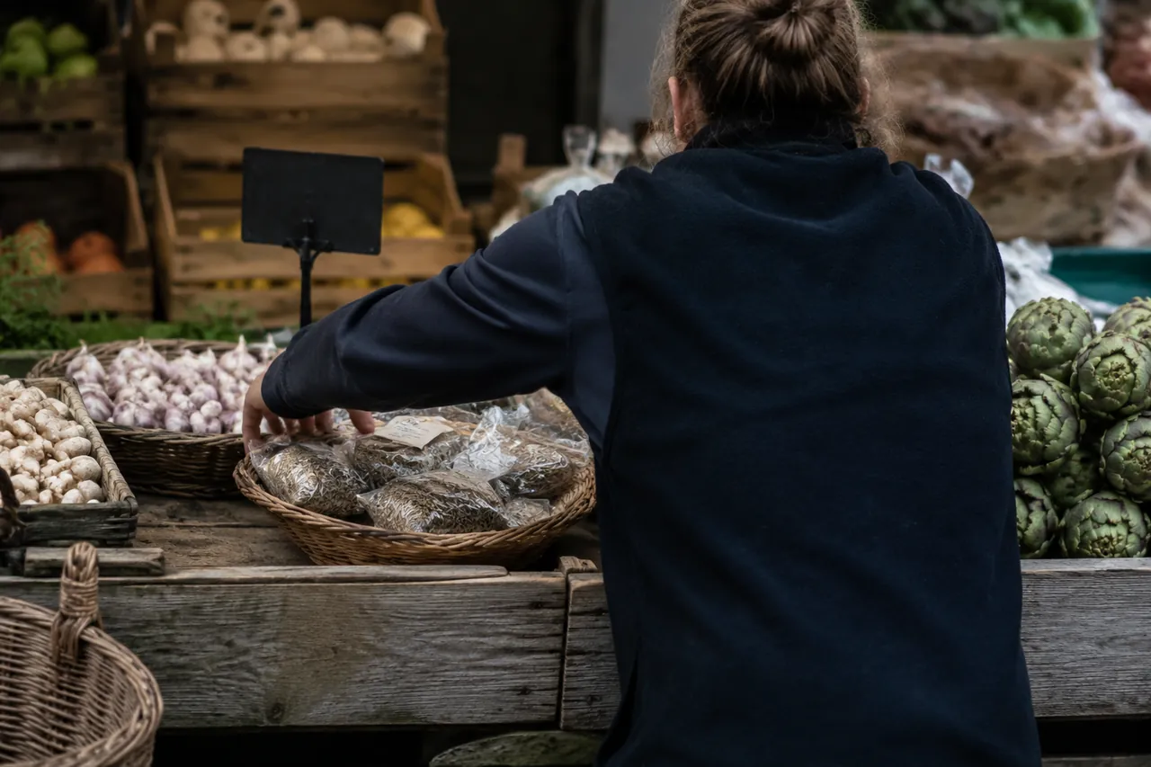 Vendeur disposant des produits locaux sur un étal rustique de marché provençal matinal