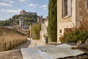 Sunlit travel-planning scene in Villeneuve-lès-Avignon with a map in the foreground and historic Provençal architecture in th