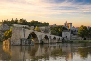 Vue du Pont Saint-Bénézet à Avignon depuis les berges du Rhône, montrant ses arches interrompues et les remparts en arrière-p