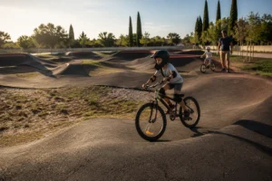 Famille utilisant une pump track asphaltée à la Plaine des sports d’Avignon, avec un jeune débutant équipé d’un casque et de